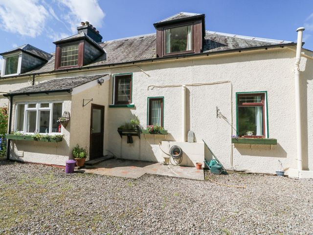 The exterior view of a house with gravel ground and three windows with flower boxes and a door at Callart View in Glencoe