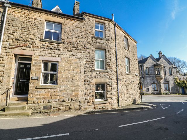 A stone building with windows and door on a street at Corner Cottage Tideswell