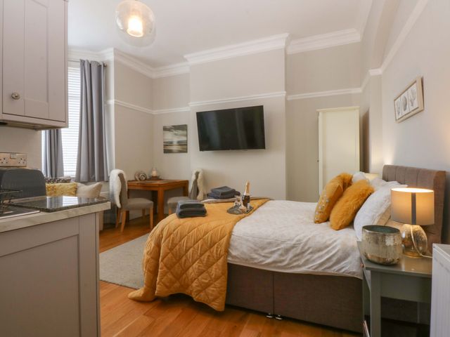 A bedroom with a bed and kitchenette at Queens Park Llandudno