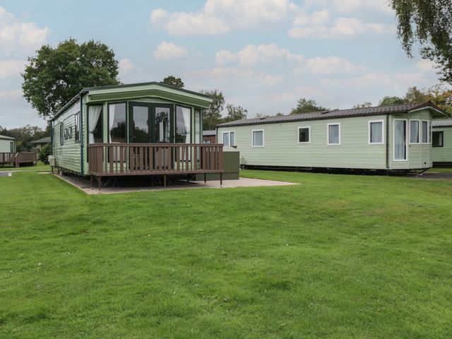 Green static caravans on a grassy plot with trees in the background at Mallard in Shobdon