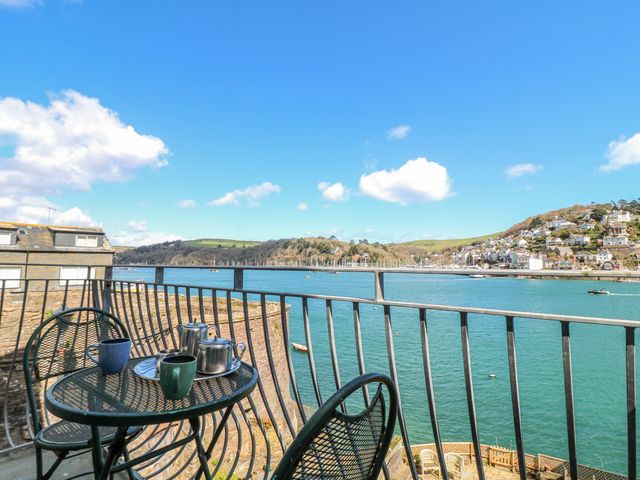 A balcony with a table and chairs overlooking a river at Harbourside Dartmouth