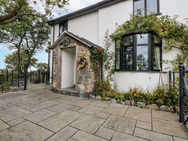 An outdoor entrance with stone pathway and flower arrangement at Windyridge in Gwaenysgor, near Prestatyn