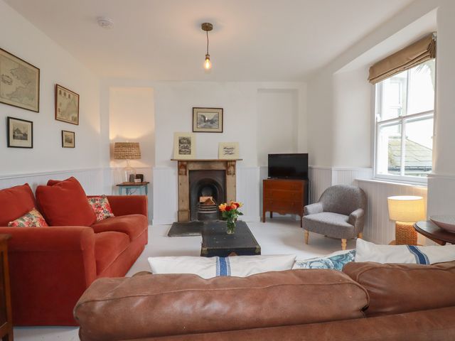 A living room with a sofa, armchair, coffee table, and fireplace at 84 Fore Street