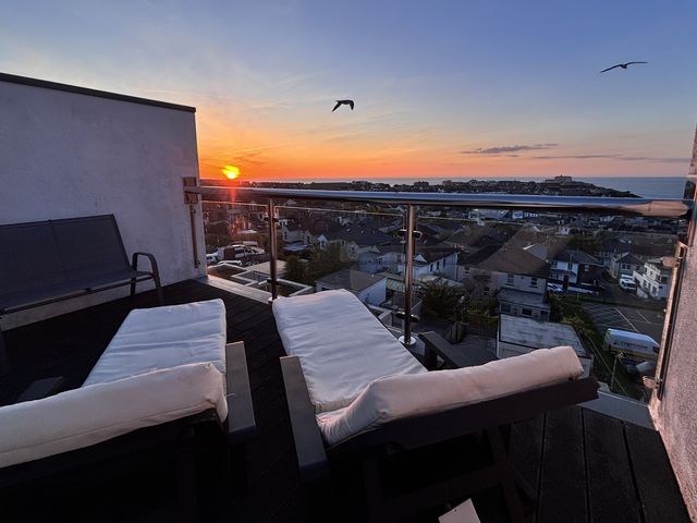 An outdoor area with lounge chairs and a view of the sunset at 10 Quay Court in Newquay