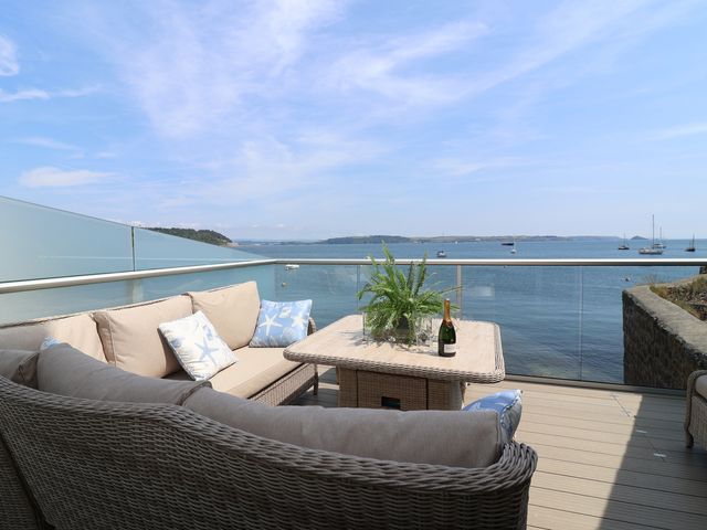 A balcony with a sofa and table overlooking water and boats at Marina