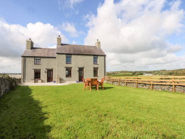 A house with a table and chairs in the garden at Trefor Ganol Beaumaris