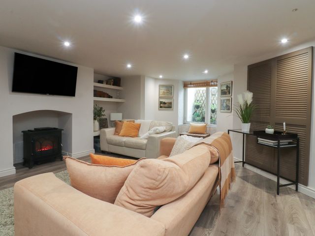 A living room with a sofa, television, and fireplace at Paramount Apartments in Lytham St. Annes