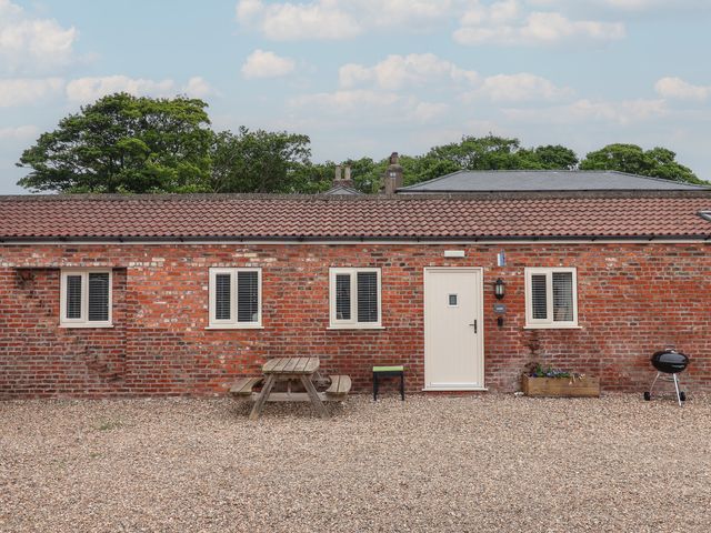 An outdoor view of a brick building with a table and grill at Gannet in Flamborough