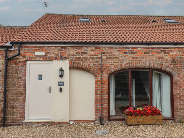 An outdoor view of a brick building with a door and window at Kittiwake Flamborough