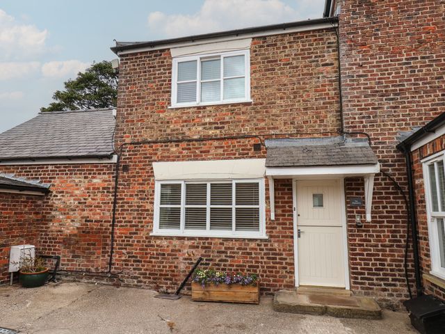 An exterior view of a red brick building with a door and flower box at The Pheasantry in Flamborough