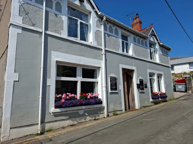 A building with flower boxes on a street at Penrhyn Arms Apartment in Penrhyn Bay