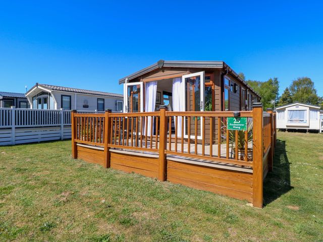 A caravan with a wooden deck and sign at 25 Foxburrow Hang in Fritton near Belton