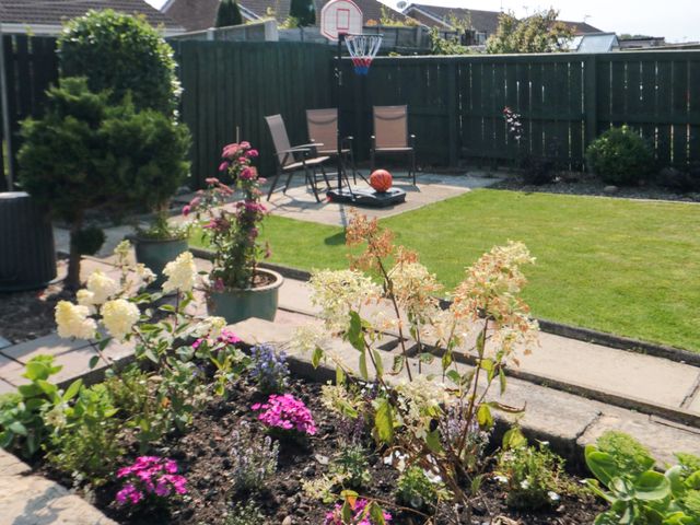 A garden with flower beds lawn chairs a basketball hoop and a basketball at 36 Chatsworth Close Bridlington