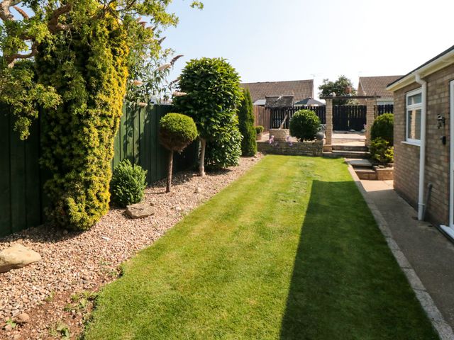 A garden with lawn and trimmed bushes next to a brick house at 36 Chatsworth Close Bridlington