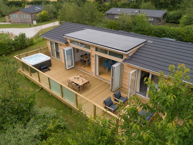 A wooden deck with hot tub dining table and seating outside a single story house at 5 Southern Place in Dobwalls
