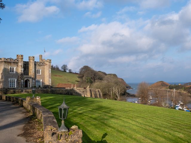 A stone castle next to a grassy hill with lamp posts and a view of the sea at Watermouth Castle Penn Curzon Apartment Berrynarbor near Ilfracombe