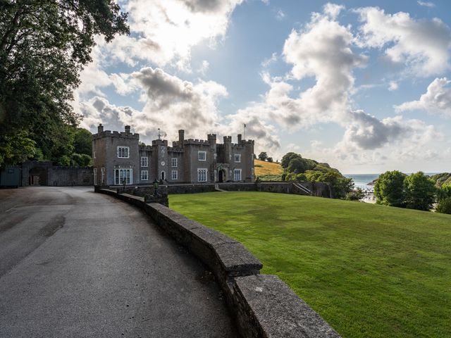 A castle with a driveway and lawn overlooking trees and the sea at Watermouth Castle South Court Apartment in Berrynarbor near Ilfracombe