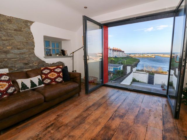A living room with a sofa and large window at Island House in Aberaeron