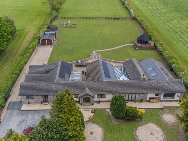 An aerial view of a house with a garden and playground at Brookway Lodge, Caerwys