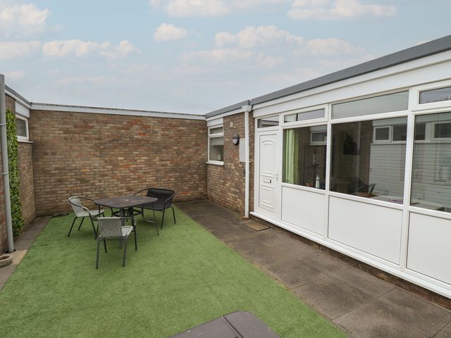 An outdoor patio area with seating and a door at Seaside Retreat Chapel Point near Chapel St Leonards