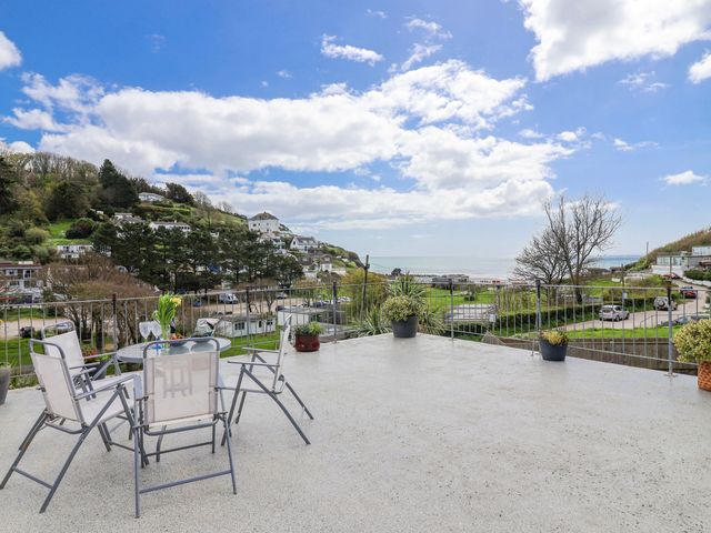 An outdoor terrace with seating and a view of the sea at Shells Cottage in Looe