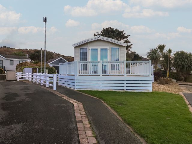 A static caravan with a white fenced deck in a caravan park with palm trees and other caravans at Seaviews in Nefyn