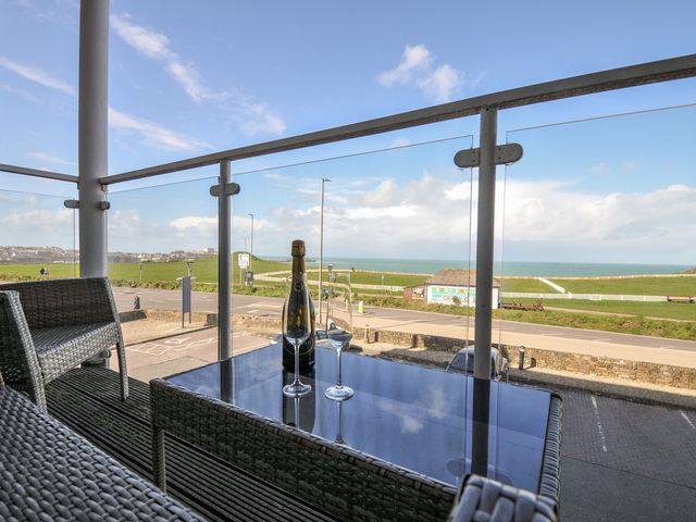 A balcony with wine and glasses overlooking the sea at Whitewater Seaview in Newquay
