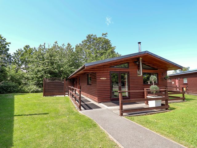 A log cabin with a pathway and grassy area at The Roe Llanerch Park near St Asaph