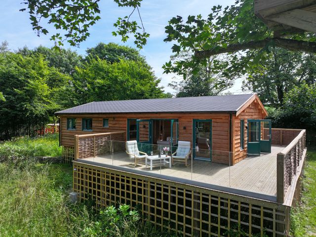A house with a deck and chairs at Owl Lodge Menheniot