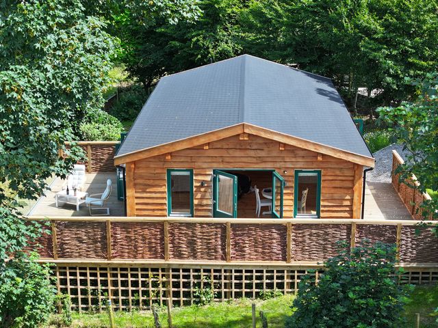 A log cabin with a deck and chairs at Owl Lodge Menheniot