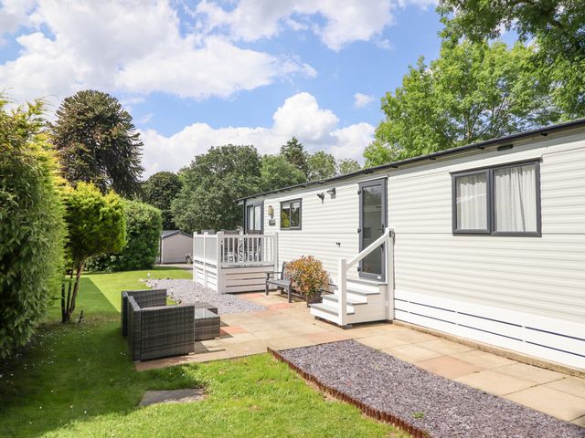 A garden area with patio furniture and a white mobile home at Woodlands Lodge in Bontuchel near Ruthin