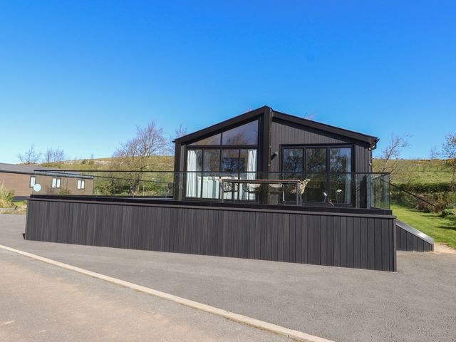 A house with a deck and glass railing at Encil Gyfrinfa in Gwynus, near Llithfaen