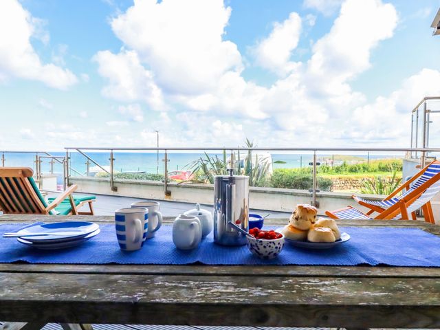 A balcony with a table set for breakfast with coffee and pastries at 4 Ocean Gate in Newquay