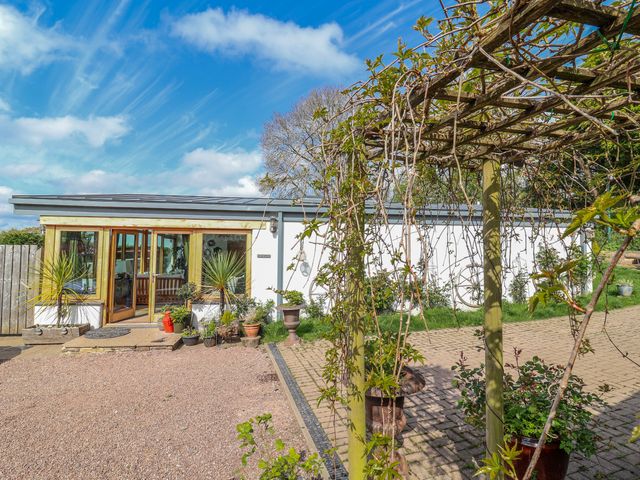 An outdoor area with a house, patio, and planters at Burlodge, Swimbridge near Barnstaple
