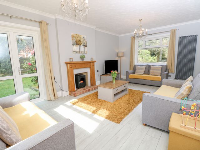 A living room with three sofas a coffee table a fireplace and large windows at Morningside in Totland Bay