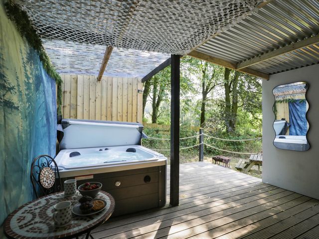 An outdoor area with a hot tub and table at Squirrels Lodge in South Molton