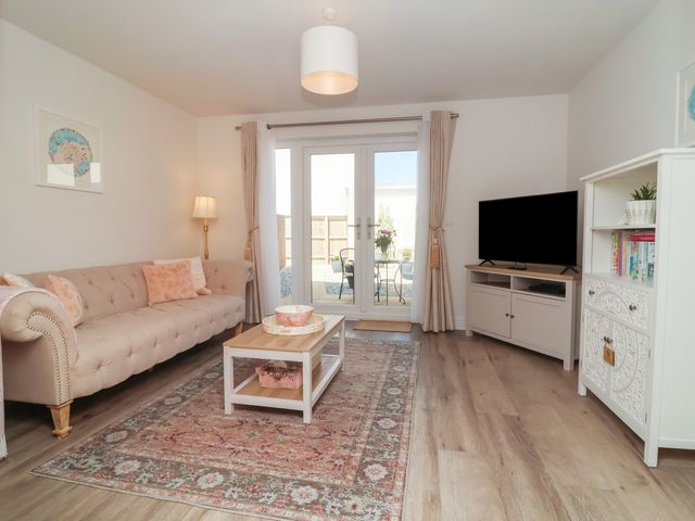 A living room with a sofa, coffee table, and TV stand at Seashell Sands in Appledore