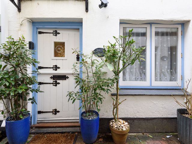 An entrance door with plants and a sign at Dolls Cottage in Looe