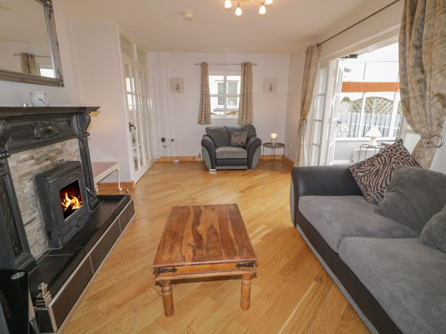A living room with a wooden coffee table a grey sofa and armchair a fireplace and curtains at 2 Carlton Cottage Enniskillen