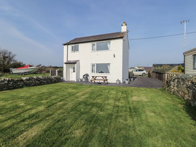 A two-story house with windows and a patio table at Pentre Iago in Rhoscolyn