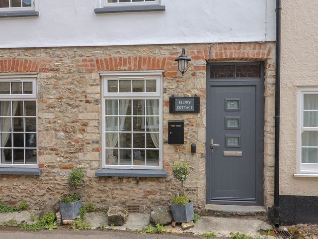 A front view of a cottage with stone walls and windows at Belfry Cottage in Colyton