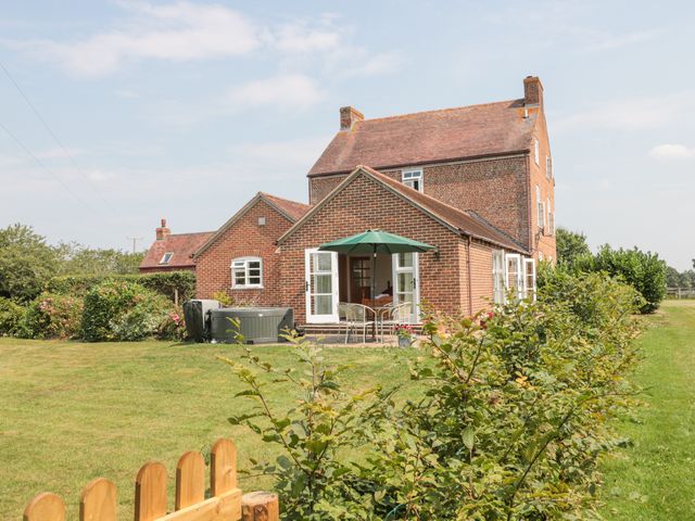 A brick house with multiple windows and a patio with a green umbrella and chairs at Orchard View in Redmary D'Abitot near Hartpury