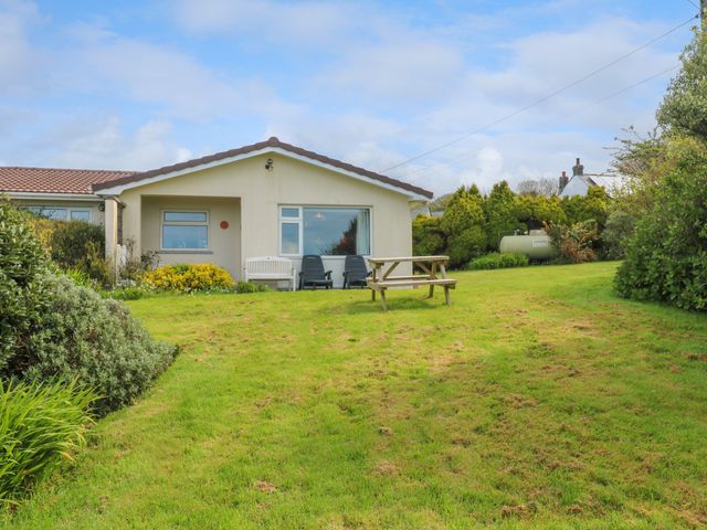 A house with a lawn and outdoor seating including a bench and two chairs with a picnic table on the grass at Merriview Ashton Nr Helston