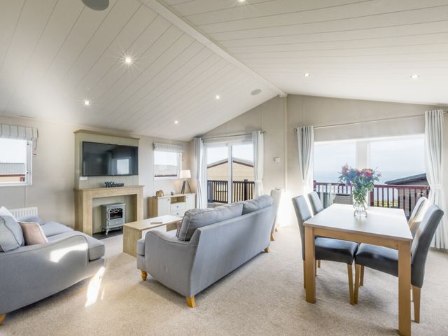 A living room with a television and a dining table at Lodge 72 at Riviera Bay Coastal Retreat in Brixham