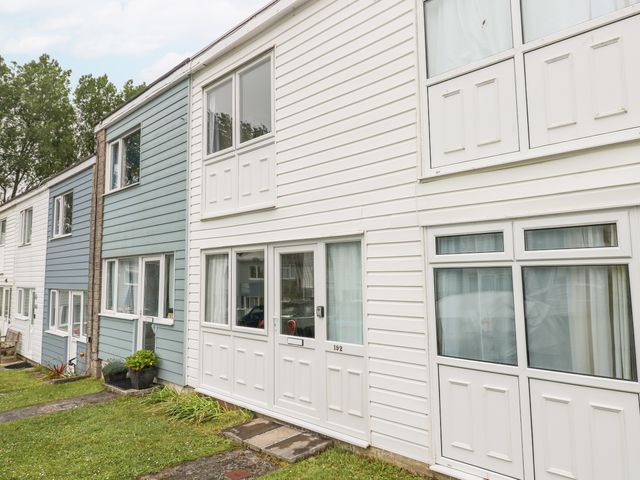 A row of residential townhouses with white and blue siding and a grass lawn in front at The Chalet in Freshwater East near Lamphey