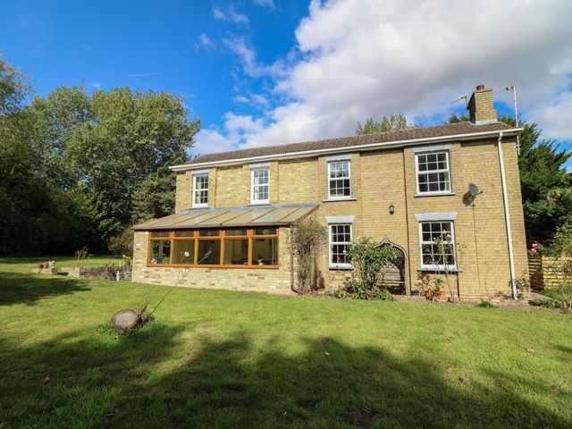 A house with a glass conservatory and garden at Larkspur Cottage in Alford
