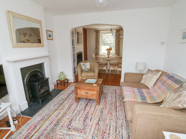A living room with a fireplace armchair sofa and coffee table connected to a dining area at 14 Ferndale in Dartmouth