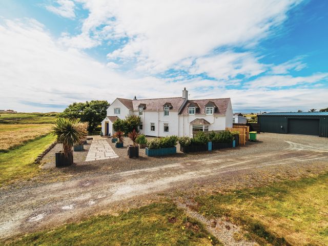 An outdoor view of a house with garden and garage at Glanllyn Bach Llanfaelog