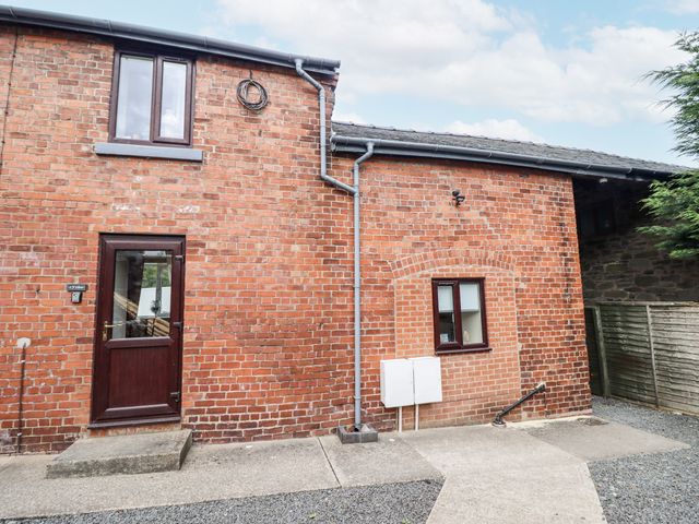 An exterior view of a brick building with a door and windows at 1 Y Llew in Llandinam