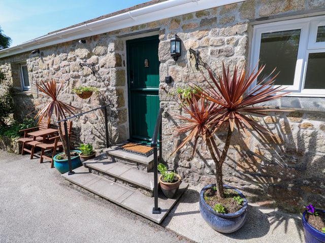 Stone exterior wall with green door steps potted plants and a wooden bench at Chy-An-Oula in Seworgan near Constantine